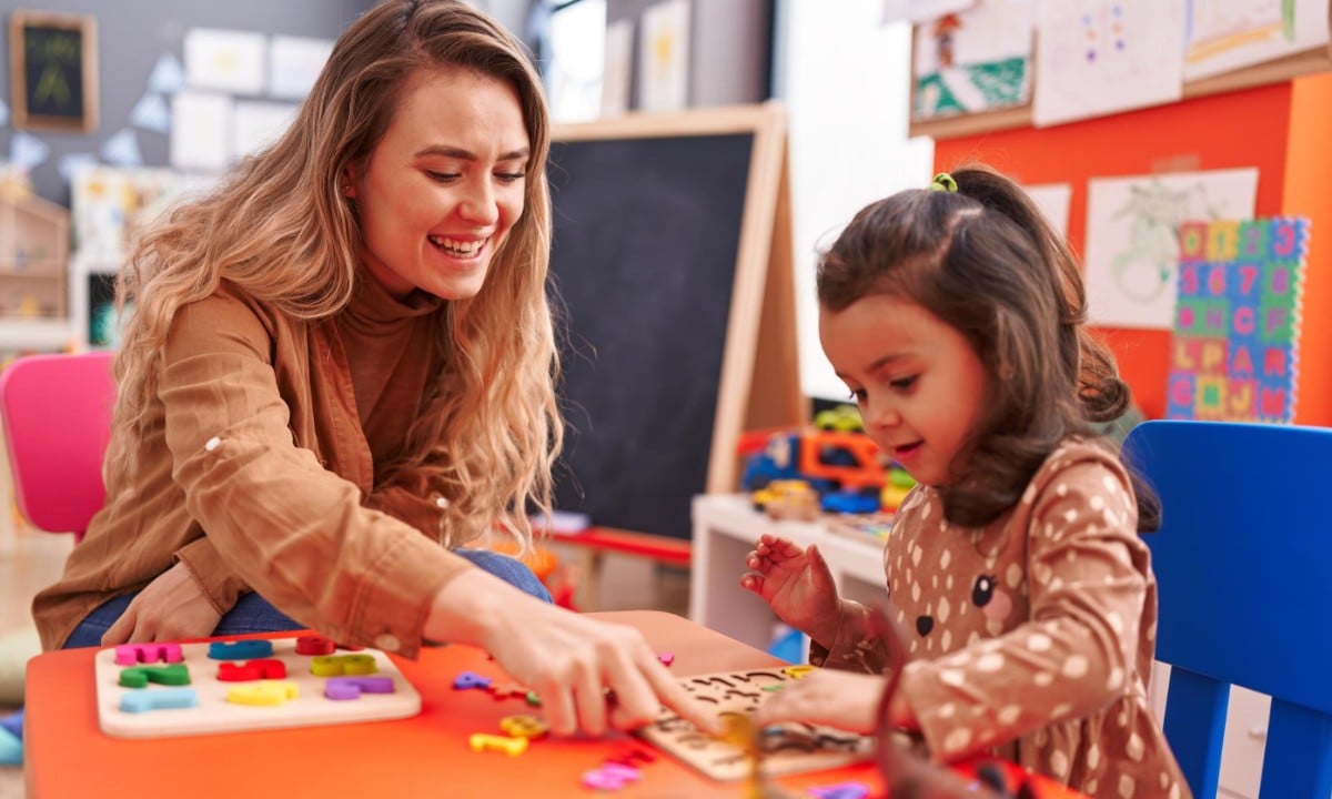 Early learning teacher working one on one with a toddler on a puzzle activity